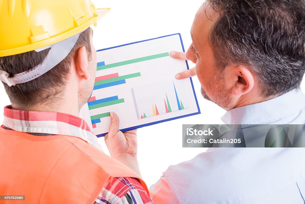 Contractor and foreman checking financial charts Contractor and foreman checking financial charts or construction development 2015 Stock Photo