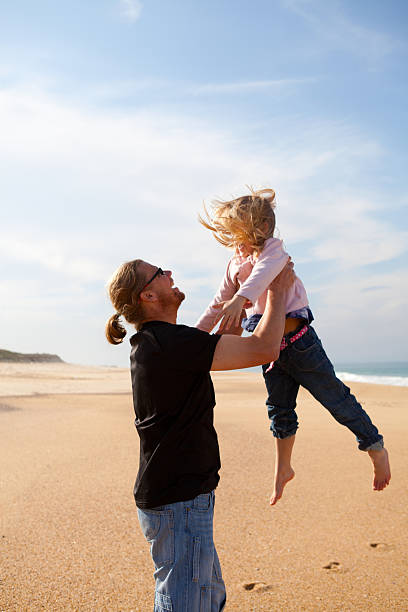 istock Father throwing daughter in the air at beach 474705513