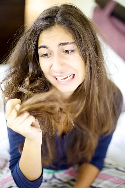 Young woman desperate about her ruined hair full of split ends