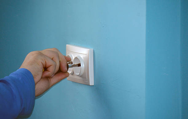 istock electrician fixing a socket cover on the wall 474714822