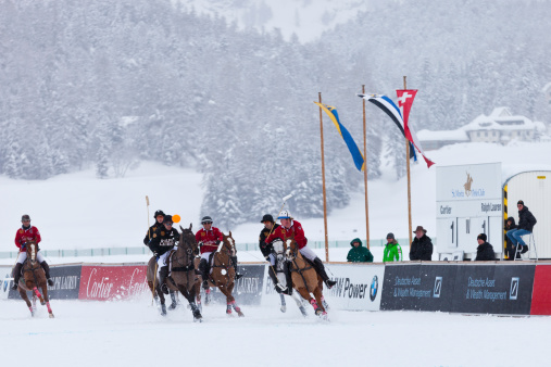 St. Moritz, Switzerland - February 2, 2014:  Tied at 1:1 in the fourth chukker of the final of the St. Moritz Polo World Cup on Snow players from team Ralph Lauren and team Cartier chase after the ball. The St. Moritz Polo World Cup on Snow is the world’s most prestigious winter polo tournament. Four high-goal teams with handicaps between 15 and 18 goals battle for the coveted Trophy on the frozen surface of Lake St. Moritz.