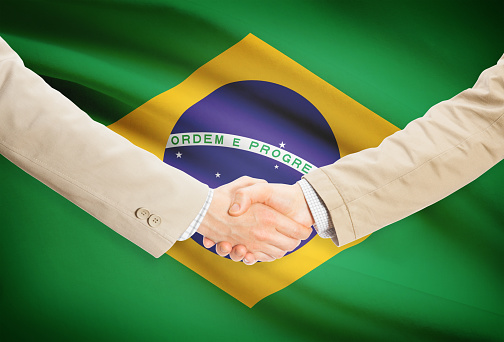 Businessmen shaking hands with flag on background - Brazil