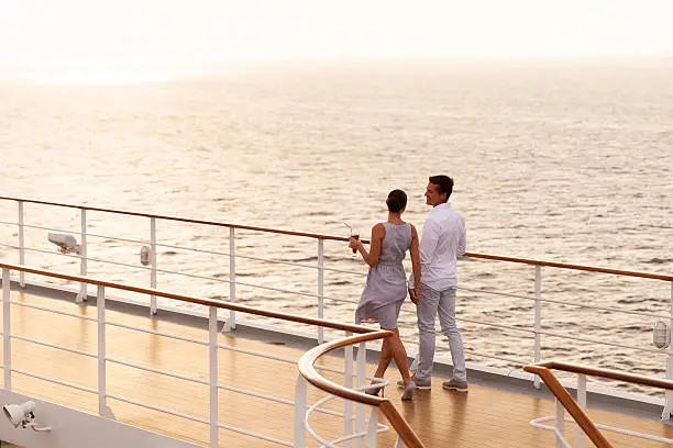 cute couple walking on cruise ship deck at sunset