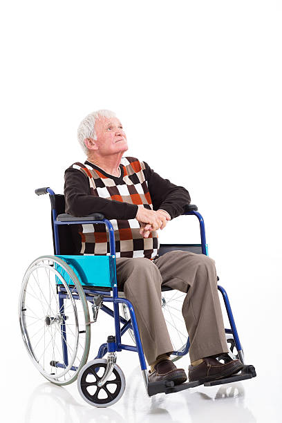 old handicapped man sitting on wheelchair in the park and looking somewhere, sepia tone
