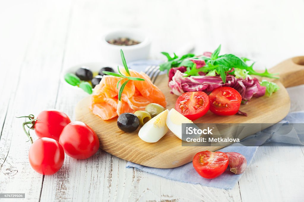 Salad with salmon Ingredients for salad with salmon, cherry tomatoes and lettuce on a wooden chopping board on rustic white background, selective focus 2015 Stock Photo