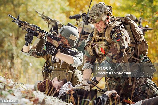 Soldier Provides Medical Care To Wounded Afghan Soldiers Stock Photo - Download Image Now