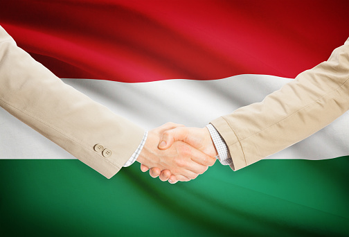 Businessmen shaking hands with flag on background - Hungary