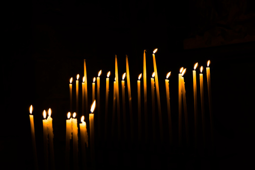 Burning candles in a dark chapel in France.  Large clean black area for copy.