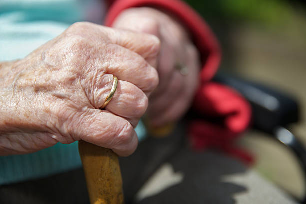 istock Elderly hands grip a walking stick in the sunlight 474745438