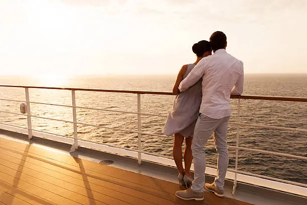 back view of young couple hugging at sunset on cruise ship