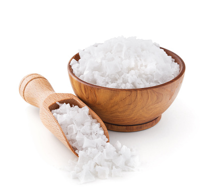 Cyprus sea salt flakes in a wooden bowl isolated on white background