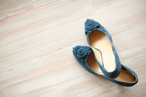 Blue suede leather women shoes isolated on white wooden floor.