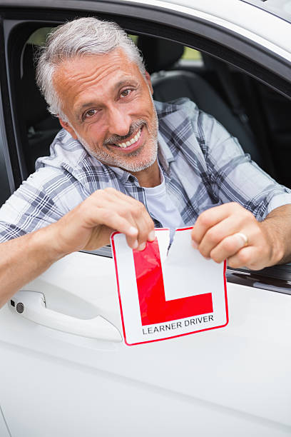 istock Driver smiling and tearing l plate 474752730