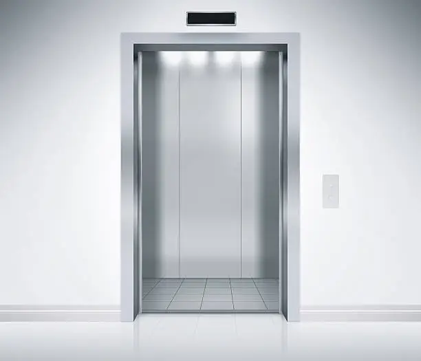 An empty modern elevator or lift with metal doors that are open in building with lighting.