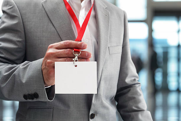 Businessman holding blank ID badge Businessman at an exhibition or conference showing a blank security identity name card on a lanyard badge photos stock pictures, royalty-free photos & images