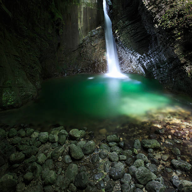 istock Romantic waterfall flowing through a crevasse to green lake 474761602