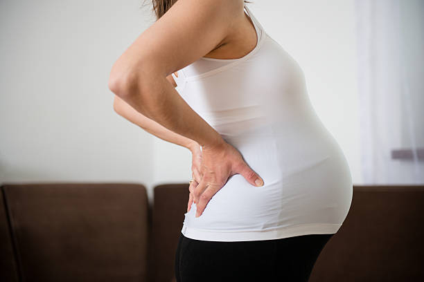 rückenschmerzen in der schwangerschaft - abdomen women massaging human hand stock-fotos und bilder