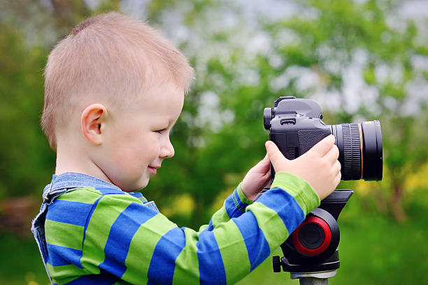 istock Pretty boy shooting with camera on meadow in spring 474771522