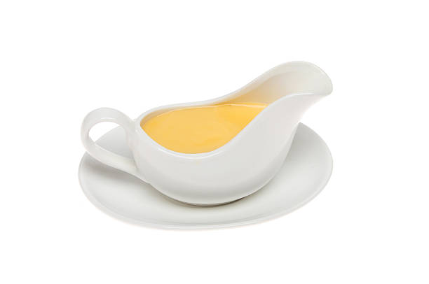 Yellow sauce Yellow sauce in a sauce boat, could be custard or Hollandaise, isolated against white hollandaise sauce stock pictures, royalty-free photos & images