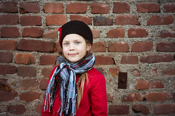 girl in red coat portrait close to the old red  brick wall