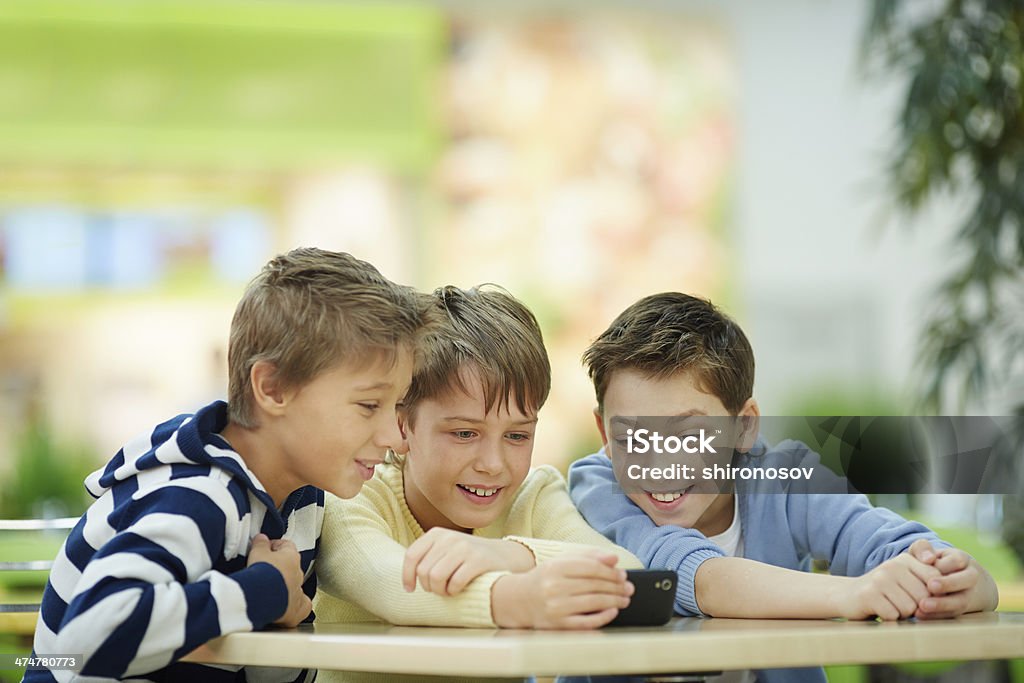 Interesting video Three boys absorbed in smartphone screen Boys Stock Photo