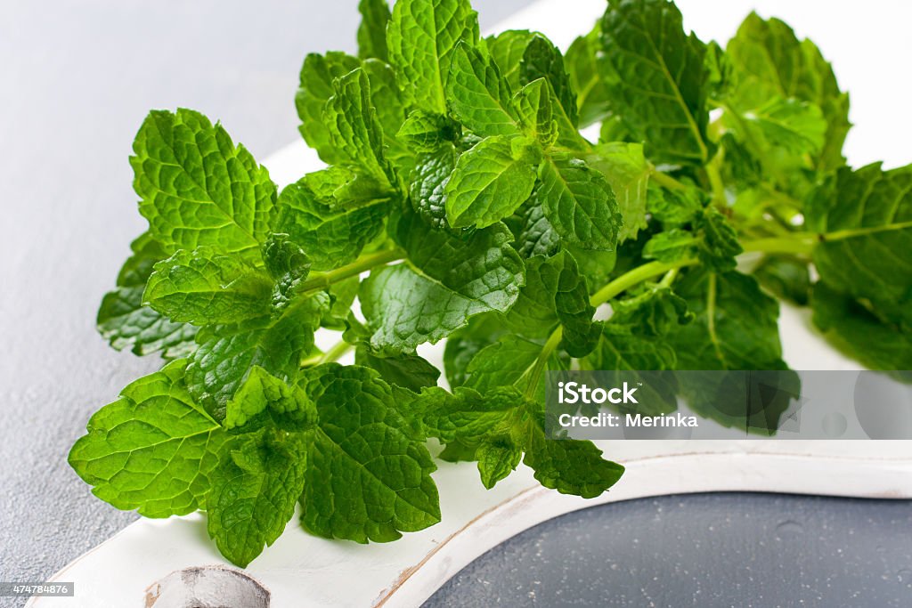Fresh mint on white cutting board Fresh mint on white cutting board on gray background 2015 Stock Photo