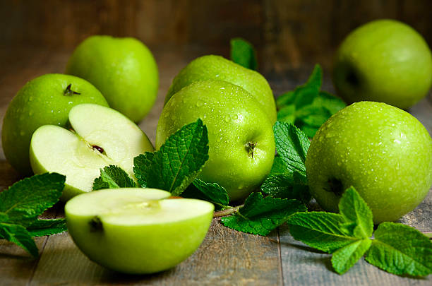 зеленые яблоки с листьев мяты. - granny smith apple стоковые фото и изображения