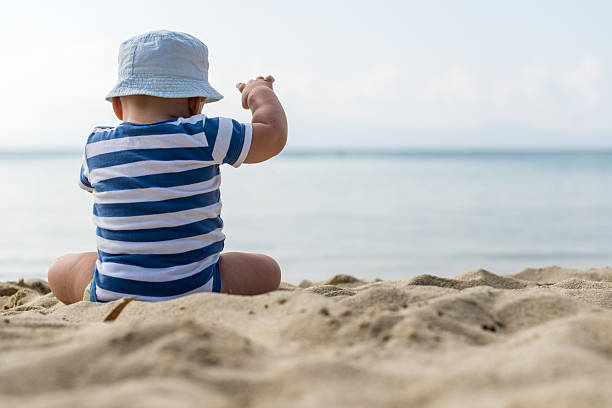 istock Baby boy with hat sitting on the beach 474798814