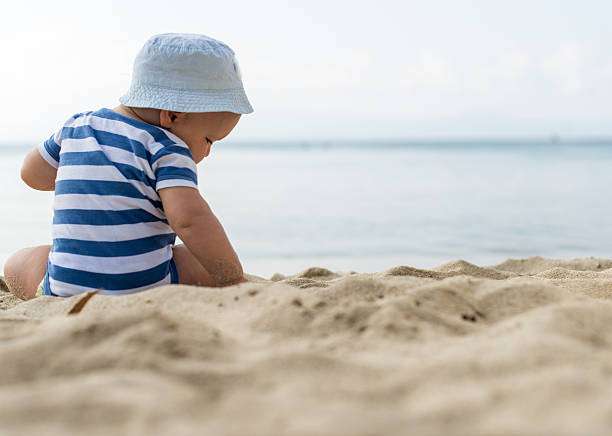 istock Baby boy with a hat sitting on the beach 474798834
