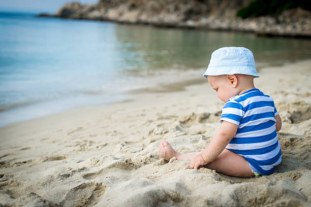 istock Baby boy with hat sitting on the beach 474798840