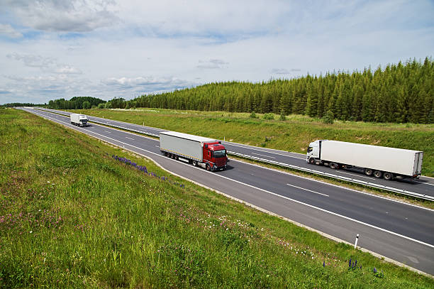 istock Asphalt highway rising flowering meadows. Three trucks on the road. 474799122