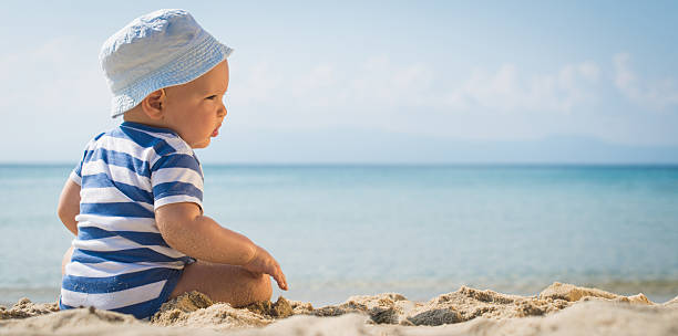 istock Baby boy with a hat sitting on the beach 474803446