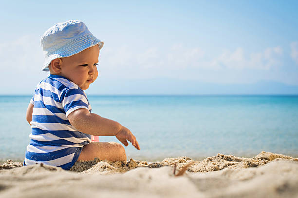 istock Baby boy with hat sitting on the beach 474803450