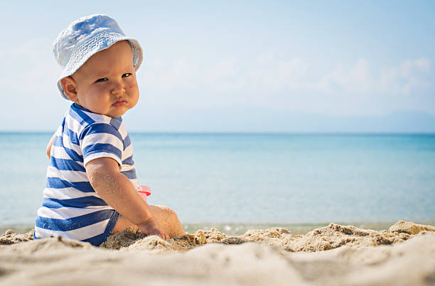 istock Baby boy with hat sitting on the beach 474803458