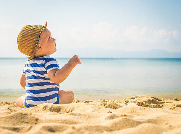 pequeno bebê menino sentado na areia - roupa morna imagens e fotografias de stock