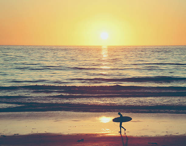 istock San Diego Surfer Walking on beach to ocean at sunset 474807122