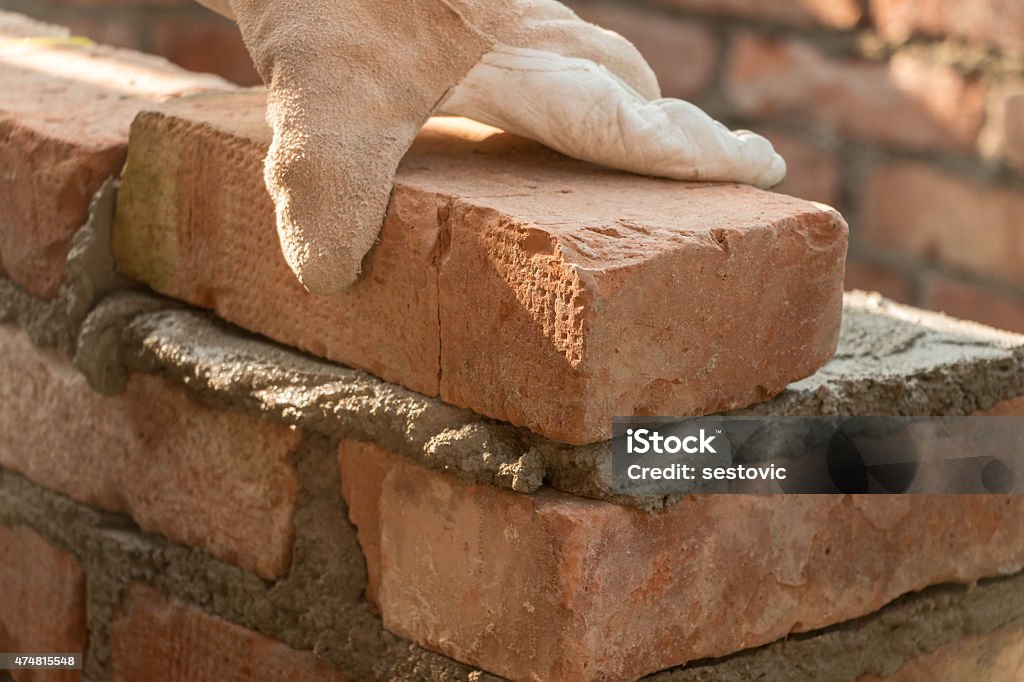 Bricklaying Man is building a wall of bricks Mason - Craftsperson Stock Photo