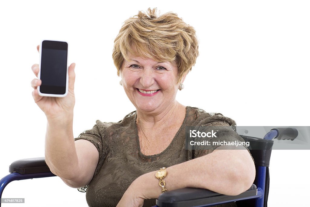 elderly woman in a wheelchair showing smart phone pretty elderly woman in a wheelchair showing smart phone on white background 70-79 Years Stock Photo