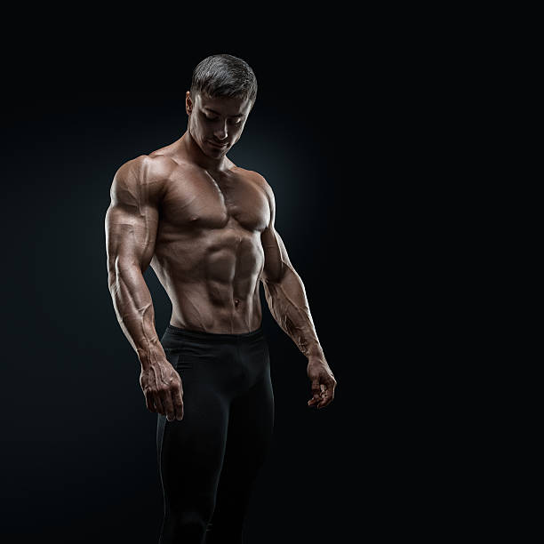 ajuste jovens bodybuilder posando sobre fundo preto - human muscle abdominal muscle men exercising - fotografias e filmes do acervo