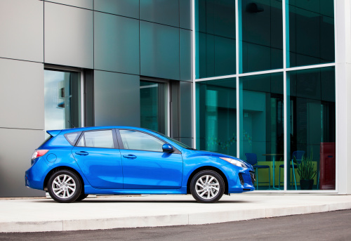 Dartmouth, Nova Scotia, Canada - September 9, 2012: A new 2013 Mazda 3 hatchback vehicle on a car dealership lot displayed in front of the showroom.  Vehicle is on prominent display in front of dealership and inside front window a sitting area can be seen. Known as the Alexa in Japan is was introduced as a 2004 model. Model pictured is the second generation of the Mazda 3.