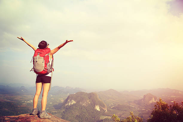 istock cheering woman hiker open arms at mountain peak 474843062