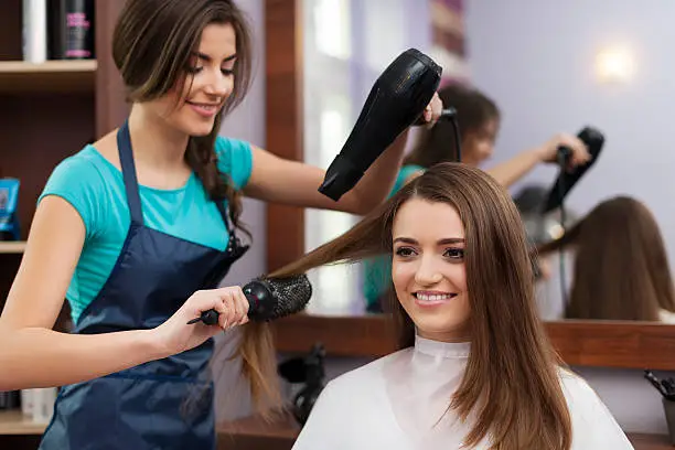 Photo of Female hairdresser using hairbrush and hair dryer