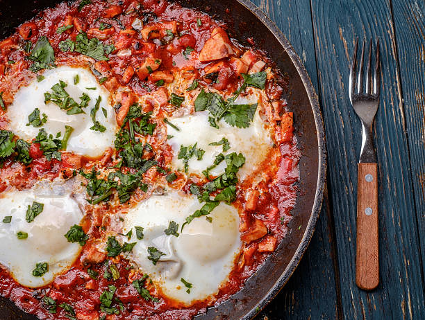 istock Fried eggs in a frying pan with tomatoes 474847464