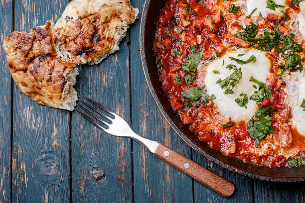 istock Fried eggs in a frying pan with tomatoes 474847474
