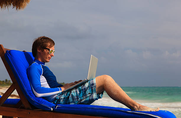 istock man with laptop on beach vacation 474848354