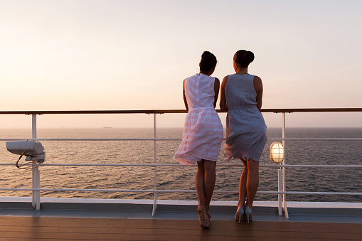 rear view of women looking at sunrise on a cruise ship