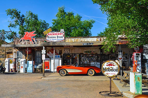 Barstow, California, USA - August 15, 2018: Barstow Sign with 1961 Corvette Convertible along Route 66. Barstow is located in Mojave Desert, san Bernardino County. American flag on background