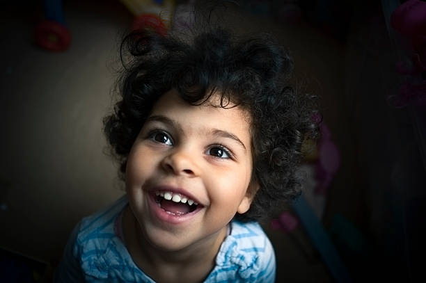 Portrait of a little girl of 3 years old taken overhead with a wide angle lens. Capturing her ecstatic happy toothy smile. This file has a signed model release.