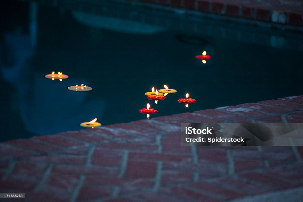 Votive Candles Floating In Swimming Pool Small tea light votive party candles floating in swimming pool during a wedding party. 2015 Stock Photo