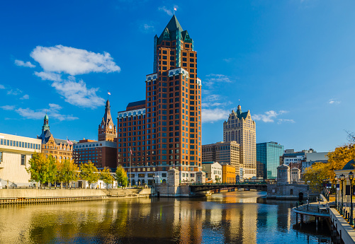 Milwaukee Center (center) with 100 East Wisconsin (on the right) and the Milwaukee City Hall (to the left), and the Milwaukee River in the foreground.  The Milwaukee City Hall, Milwaukee Center, and 100 East Wisconsin are all european influenced (Milwaukee City Hall was built in the Flemish Renaissance Revival style, Milwaukee Center was inspired by Milwaukee City Hall, and 100 East Wisconsin is postmodern that mimics German architecture.)